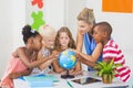 Teacher discussing globe with kids Royalty Free Stock Photo