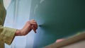 Teacher drawing on blackboard. Schoolteacher hand writing on chalkboard