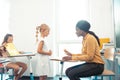 Dark-skinned teacher speaking with cute girl wearing white dress