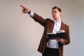 Teacher dressed in a suit on a white background holding a book while pointing somewhere. Business man pointing with a book in his Royalty Free Stock Photo