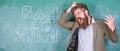 Teacher or educator stands near chalkboard with inscription back to school. Hate school. Teacher unhappy shouting Royalty Free Stock Photo