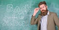 Teacher or educator welcomes students while stands near chalkboard with inscription back to school. Teacher begin first Royalty Free Stock Photo