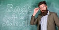 Teacher or educator welcomes students while stands near chalkboard with inscription back to school. Teacher begin first Royalty Free Stock Photo