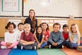 Teacher and elementary school kids sitting on classroom floor