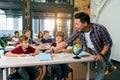 Teacher of elementary school puts notebooks on desks pupils for learning. Group of schoolchildren primary school sitting Royalty Free Stock Photo