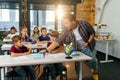 Teacher of elementary school puts notebooks on desks pupils for learning. Group of schoolchildren primary school sitting Royalty Free Stock Photo