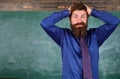 Teacher etiquette tips modern education professional. Man bearded teacher or educator hold head chalkboard background Royalty Free Stock Photo