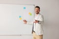 Happy teacher explaining something at whiteboard in classroom. Space for text Royalty Free Stock Photo