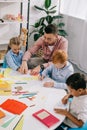 teacher in eyeglasses helping multicultural preschoolers with drawing at table Royalty Free Stock Photo