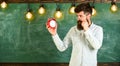 Teacher in eyeglasses holds alarm clock. Schedule and regime concept. Man with beard and mustache on concentrated face