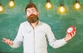 Teacher in eyeglasses holds alarm clock. Schedule and regime concept. Man with beard and mustache on confused face