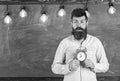 Teacher in eyeglasses holds alarm clock. Schedule and regime concept. Man with beard and mustache on surprised face in