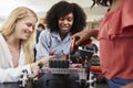 Teacher With Female Pupils Building Robotic Vehicle In Science Lesson