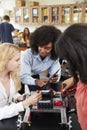 Teacher With Female Pupils Building Robotic Vehicle In Science Lesson