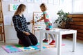 Teacher and girl do exercise on magnetic board. Child learn english alphabet and numbers in kindergarten. Young woman