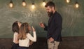 Teacher and girls pupils in classroom near chalkboard. Man with beard in formal suit teaches schoolgirls physics