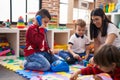 Teacher with group of boys playing with toys sitting on floor at kindergarten Royalty Free Stock Photo