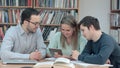 Teacher with group of students working on digital tablet in library Royalty Free Stock Photo