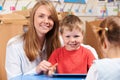 Teacher Helping Elementary Scool Pupil To Use Digital Tablet Royalty Free Stock Photo