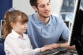 Teacher helping girl using computer in class