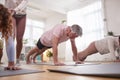 Teacher Helping Group Stretching On Exercise Mats In Yoga Or Fitness Class Inside Community Center Royalty Free Stock Photo