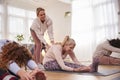 Teacher Helping Group Stretching On Exercise Mats In Yoga Or Fitness Class Inside Community Center Royalty Free Stock Photo