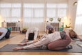 Teacher Helping Group Stretching On Exercise Mats In Yoga Or Fitness Class Inside Community Center Royalty Free Stock Photo