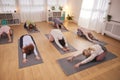 Teacher Helping Group Stretching On Exercise Mats In Yoga Or Fitness Class Inside Community Center Royalty Free Stock Photo