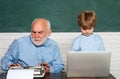 Teacher helping kids with their homework in classroom at school. Dad son are concentrated on the problem. Grandfather Royalty Free Stock Photo