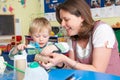 Teacher Helping Little Boy To Build Model In Art Class