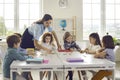 Teacher helping little primary school children group join puzzle in classroom Royalty Free Stock Photo