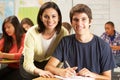 Teacher Helping Male Pupil Studying At Desk In Classroom Royalty Free Stock Photo