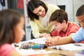 Teacher Helping Pupils Studying At Desks In Classroom Royalty Free Stock Photo