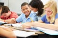 Teacher Helping Pupils Studying At Desks In Classroom Royalty Free Stock Photo