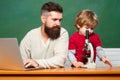 Teacher helping pupils studying on desks in classroom. Young boy doing his school homework with his father. Chalkboard Royalty Free Stock Photo