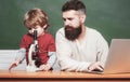 Teacher helping pupils studying on desks in classroom. Young boy doing his school homework with his father. Chalkboard Royalty Free Stock Photo