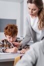 teacher helping redhead schoolboy writing in Royalty Free Stock Photo