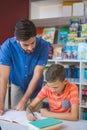 Teacher helping school kid with his homework in library Royalty Free Stock Photo