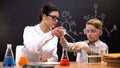 Teacher helping schoolboy dripping red substance in test tube, chemistry lesson Royalty Free Stock Photo