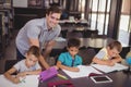 Teacher helping schoolkids with their homework in library Royalty Free Stock Photo