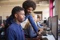 Teacher Helping Teenage Male High School Student Working In Computer Class