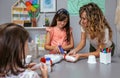 Teacher helping to girl make recycled toy robot with hot melt glue gun