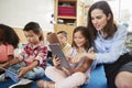 Teacher helps girl in elementary class with tablet computers