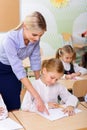 Teacher helps little girl with the task