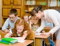 Teacher helps the schoolkids with schoolwork in classroom