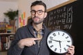 Teacher holding large clock in classroom