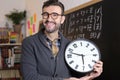 Teacher holding large clock in classroom