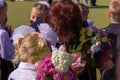 A teacher with holiday bouquet calms down crying first grade girl. First school day of russian children.