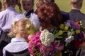 A teacher with holiday bouquet calms down crying first grade girl. First school day of russian children.