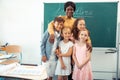 Loving happy teacher hugging her smart diligent pupils